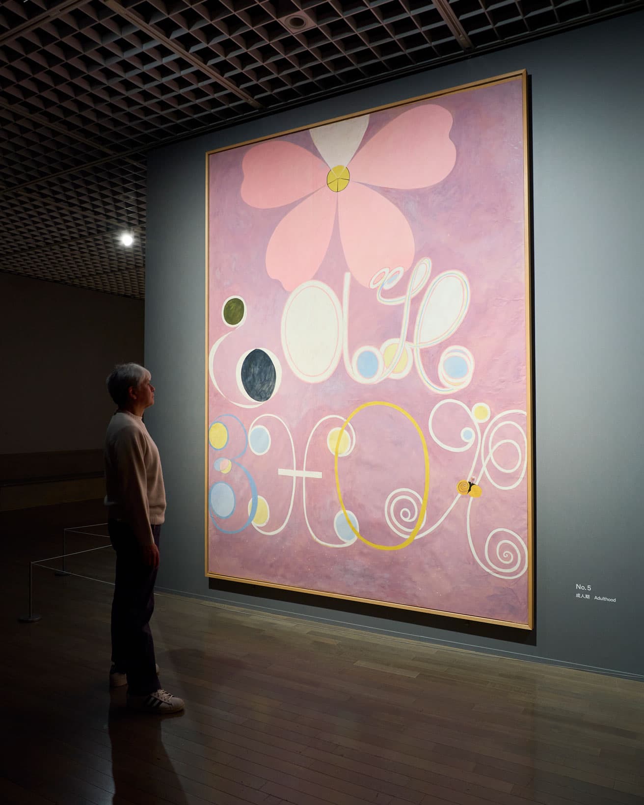 高さ3.2m、幅約2.4mの巨大な絵画シリーズ〈10の最大物〉の一枚に対峙する奈良美智。《10の最大物、グループIV、No.5、成人期》 1907年、テンペラ・紙（キャンバスに貼付）、ヒルマ・アフ・クリント財団蔵。