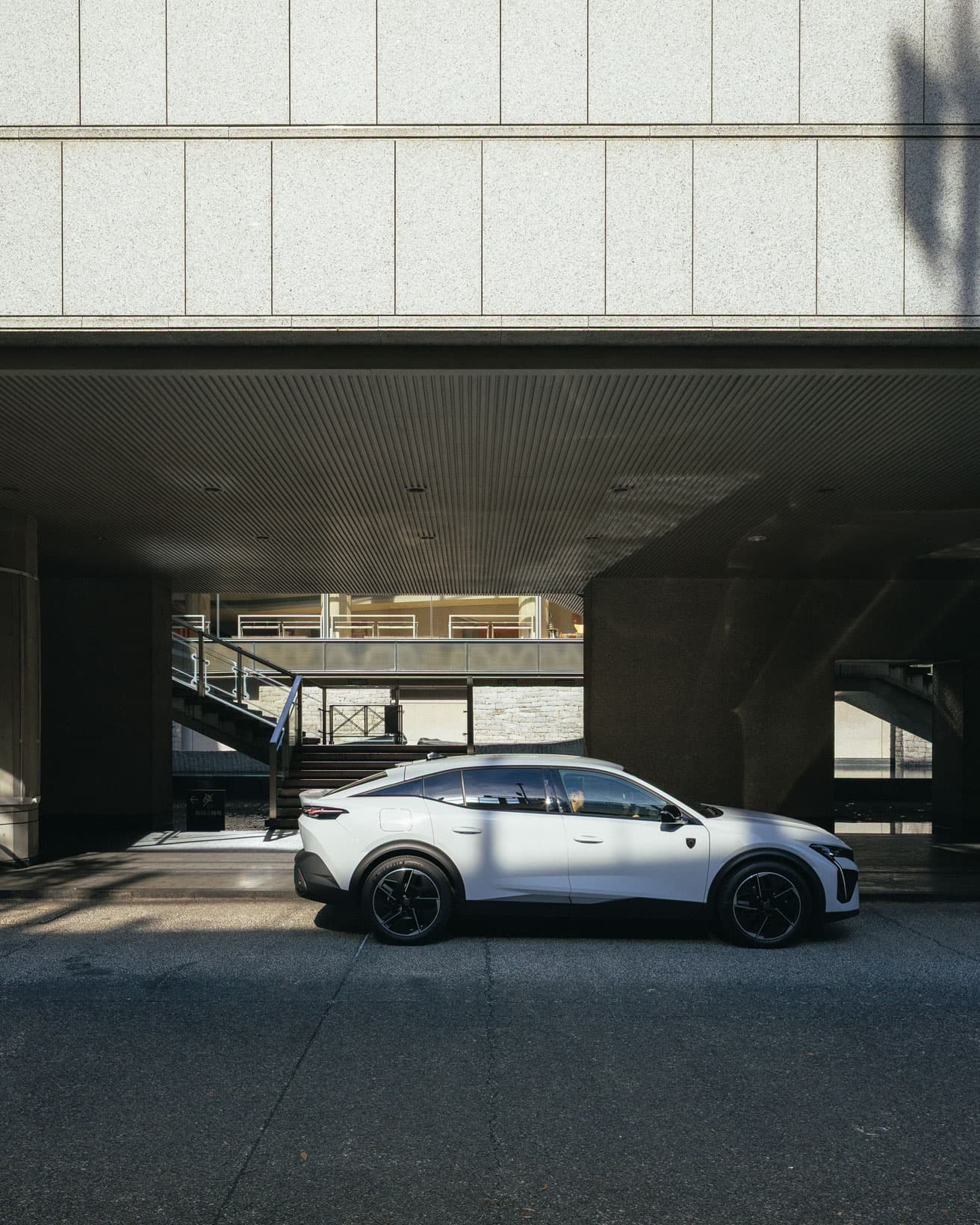 〈新国立劇場〉の車寄せに到着した《プジョー408》。直線的な建築美と対照的に、伸びやかなラインを描く。＊車寄せへの留置は特別な許可を得て撮影しています。
