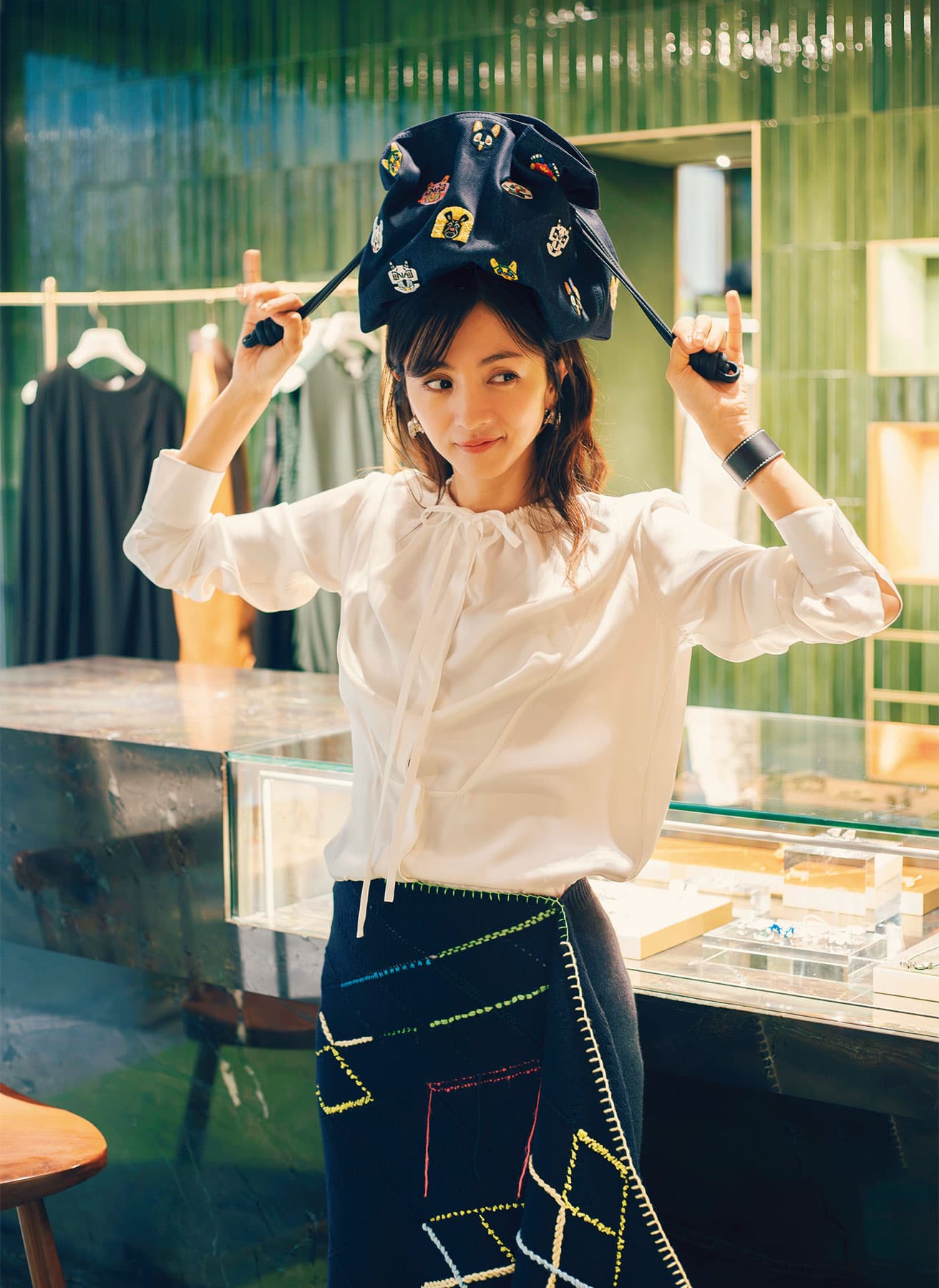 グリーンのセラミックタイルに柔らかな光が反射し、窓からは美しいパリの街並みが望める2階部分。満島さんが手にしているのは、ショーでも身につけていたバッグ《フラメンコクラッチ》の新作。バッグ48万6200円(予定価格)(ロエベ ジャパン クライアントサービス TEL 03 6215 6116)。