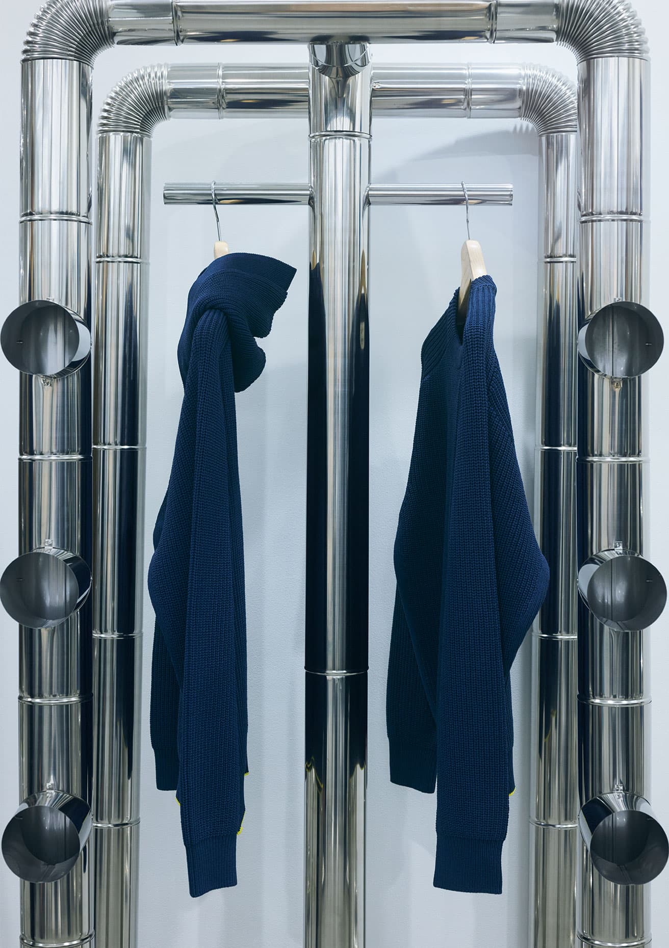 クルーネックセーターとフーディの2タイプで、カラーバリエーションは、写真のネイビー、ブラウン、ブラックの3色展開。肉厚のボディで安心感のある素材とシルエットが美しい。身頃の裾にはイエローラインがさりげなくあしらわれている。